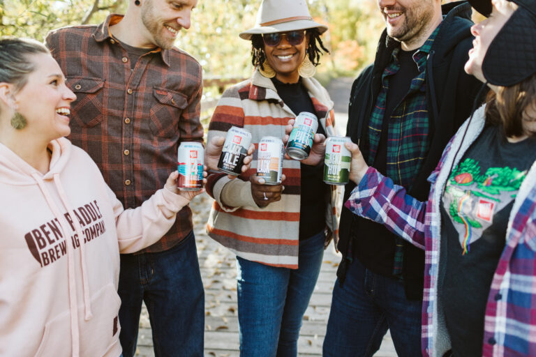 5 people holding Bent Paddle beer cans