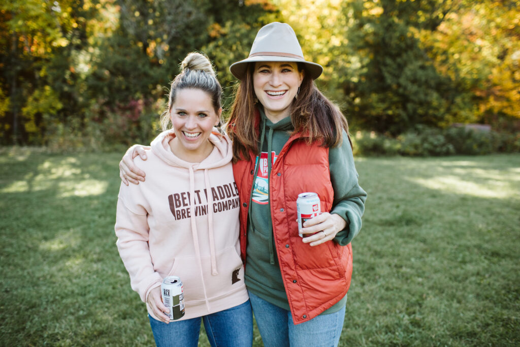 Karen and Laura Bent Paddle Brewing Co. Co-founders holding beer cans in fall