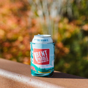 Bent paddle beer in coolie sitting on bridge in the fall